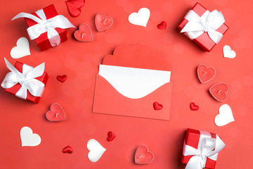 Mail envelope with a blank greeting card surrounded by gifts and hearts on a red background.