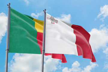 Malta and Benin flags waving in the wind against white cloudy blue sky together. Diplomacy concept, international relations.