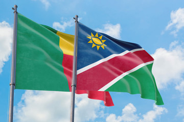 Fototapeta na wymiar Namibia and Benin flags waving in the wind against white cloudy blue sky together. Diplomacy concept, international relations.