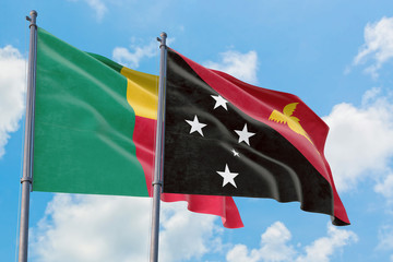 Papua New Guinea and Benin flags waving in the wind against white cloudy blue sky together. Diplomacy concept, international relations.