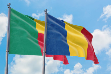 Romania and Benin flags waving in the wind against white cloudy blue sky together. Diplomacy concept, international relations.