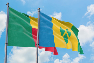 Saint Vincent And The Grenadines and Benin flags waving in the wind against white cloudy blue sky together. Diplomacy concept, international relations.