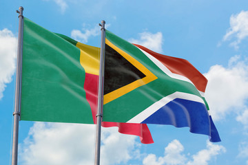 South Africa and Benin flags waving in the wind against white cloudy blue sky together. Diplomacy concept, international relations.