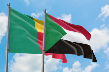 Sudan and Benin flags waving in the wind against white cloudy blue sky together. Diplomacy concept, international relations.
