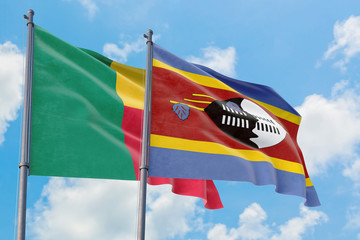 Swaziland and Benin flags waving in the wind against white cloudy blue sky together. Diplomacy concept, international relations.