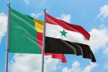 Syria and Benin flags waving in the wind against white cloudy blue sky together. Diplomacy concept, international relations.