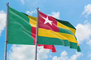 Togo and Benin flags waving in the wind against white cloudy blue sky together. Diplomacy concept, international relations.