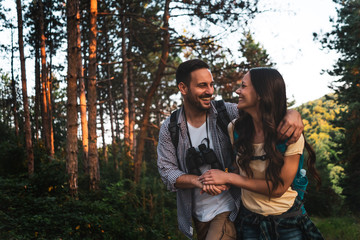 Happy couple is hiking in forest in afternoon.