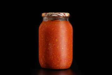 Glass jar of pickled vegetables on a black background. Preservation.