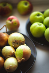 Apples and onions on a black plate