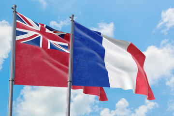 France and Bermuda flags waving in the wind against white cloudy blue sky together. Diplomacy concept, international relations.