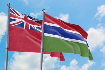 Gambia and Bermuda flags waving in the wind against white cloudy blue sky together. Diplomacy concept, international relations.