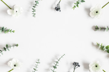 Flowers composition. Frame made of white flowers and eucalyptus leaves on gray background. Flat...