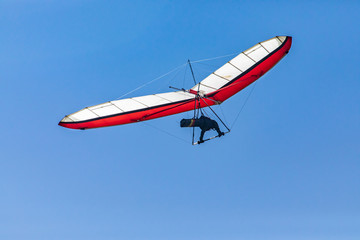 Fototapeta na wymiar Soaring hang gliding in the sky. View from the bottom. Hang glider pilot enjoying a flight. Extremal hobbies of brave people