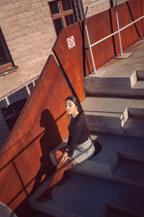 Fototapeta na wymiar stylish girl model posing sitting on the steps of the building