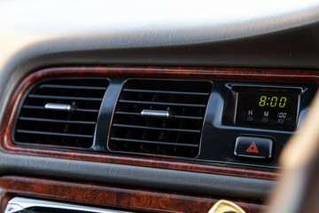 Fototapeta na wymiar A close-up view of the interior of a modern luxury car with a ventilation deflector for heating and cooling the passenger compartment with black trim and green clock digits and time eight o'clock am