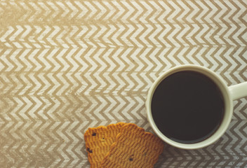  coffee n a mug, a pair of cookies on a table with zigzag ornaments, shot from above