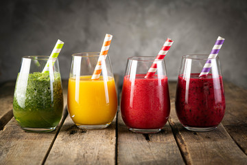Selection of colorful smoothies and ingredients in glasses, rustic background