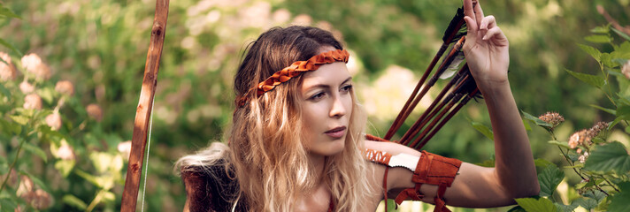 Beautiful girl archer with long blond hair with a bow and arrows dressed in leather