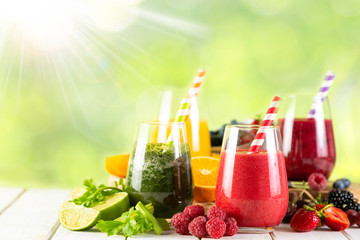 Selection of colorful smoothies and ingredients in glasses, rustic background