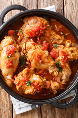 Diet rabbit meat stew in tomato sauce with white wine and herbs close-up in a pan. Vertical top view