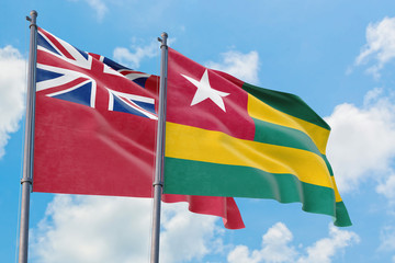 Togo and Bermuda flags waving in the wind against white cloudy blue sky together. Diplomacy concept, international relations.
