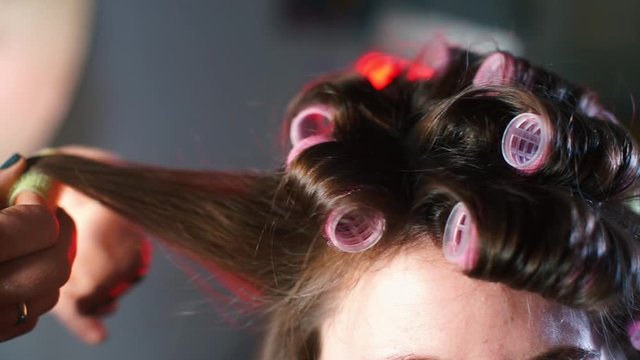 Close-up of woman hair, hairdresser winds curlers