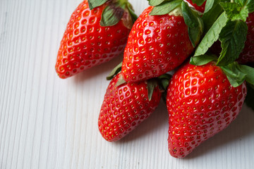 Close-up of strawberries and mint leaves, on white background and space for text in horizontal