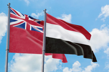 Yemen and Bermuda flags waving in the wind against white cloudy blue sky together. Diplomacy concept, international relations.