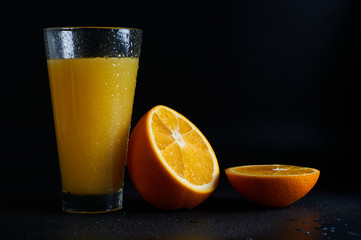 orange juice in a glass on a black background close-up