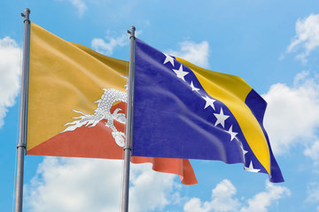 Bosnia Herzegovina and Bhutan flags waving in the wind against white cloudy blue sky together. Diplomacy concept, international relations.