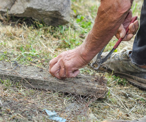 Obraz premium Old man hands holdign metal knitted wire and pliers