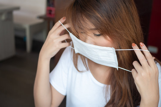 woman wearing face mask from having flu infection; concept of Wuhan virus, corona virus, H5N1, H1N1, bird flu, pig flu, avian influenza, swine influenza, pneumonia, lung inflammation, epidemic fever