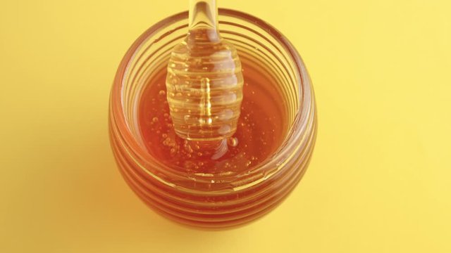 top view of honey pot full of honey and a honey dipper mixing it