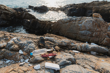 Plastic waste garbage and foam scrap on rock shore and sea beach