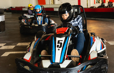 Fototapeta na wymiar active woman in helmet driving car for karting with other people
