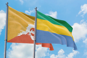Gabon and Bhutan flags waving in the wind against white cloudy blue sky together. Diplomacy concept, international relations.