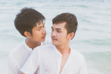 Obraz premium Homosexual portrait young asian couple standing hug and look together on beach in summer, asia gay going tourism for leisure and relax with romantic and happy in vacation at sea, LGBT legal concept.