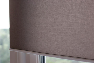 Automatic roller blinds closeup on the window. Selective fokus. Motorized shades. Beige color,...