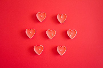 Red candles form a heart on a red background. The concept of Valentine's Day, women's day, March 8, romance, sne-in, candlelight dinner. Flatlay.