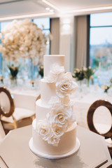 white exquisite luxury three-tier wedding cake with mastic flowers