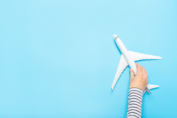 Female hand holds a plane on a blue background. Concept flight, tickets, booking, flight search,...