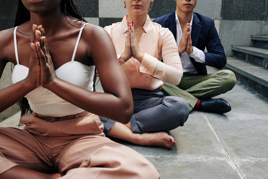 Cropped image of business people doing yoga and meditating on the floor