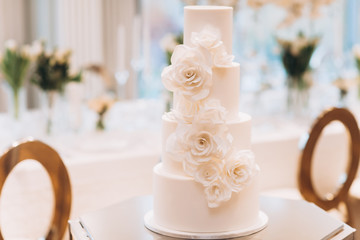 white exquisite luxury three-tier wedding cake with mastic flowers