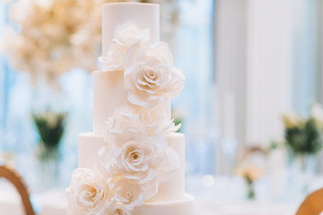 white exquisite luxury three-tier wedding cake with mastic flowers