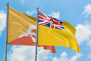 Niue and Bhutan flags waving in the wind against white cloudy blue sky together. Diplomacy concept, international relations.