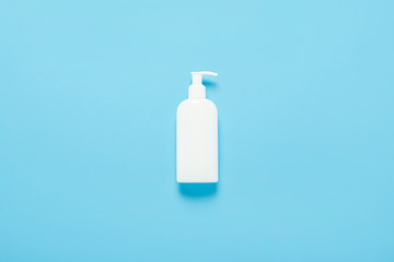 White plastic bottle with dispenser on a blue background. Concept medicine, hygiene, cosmetics, perfumery. Banner. Flat lay, top view