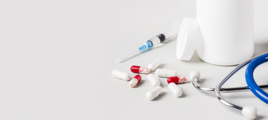 Various pills, stethoscope and syringes. Medicine treatment concept. Banner format.