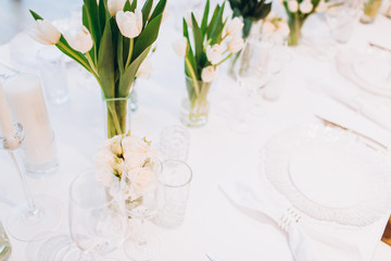 formal luxury elegant wedding decor restaurant tables served white tablecloth, plates, menus, glasses, tulips in vases, orchids, candles silver chairs, blue background