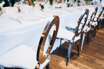 formal luxury elegant wedding decor restaurant tables served white tablecloth, plates, menus, glasses, tulips in vases, orchids, candles silver chairs, blue background